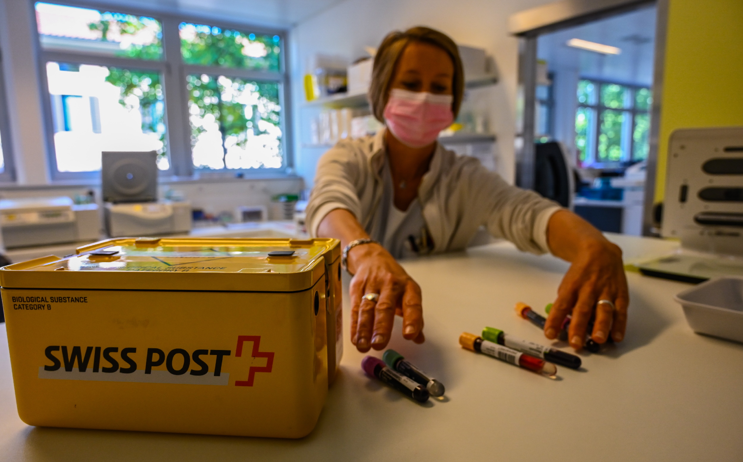 A woman sorts vials to put in a SwissPost carrier for a drone to take to another facility.
