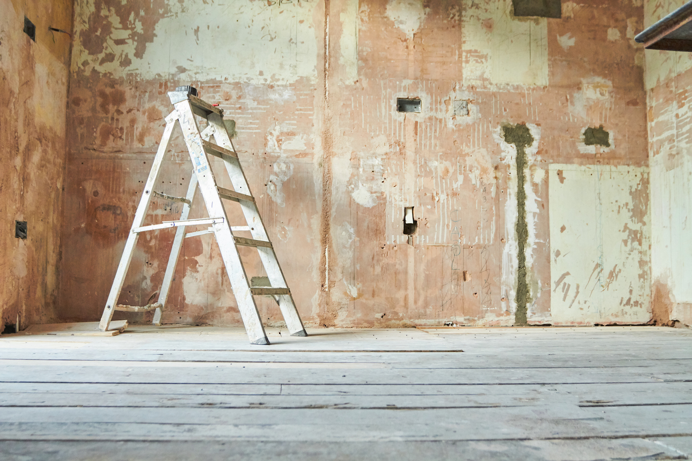 یک نردبان پله ای در یک اتاق خالی داخلی در اواسط بازسازی ایستاده است.