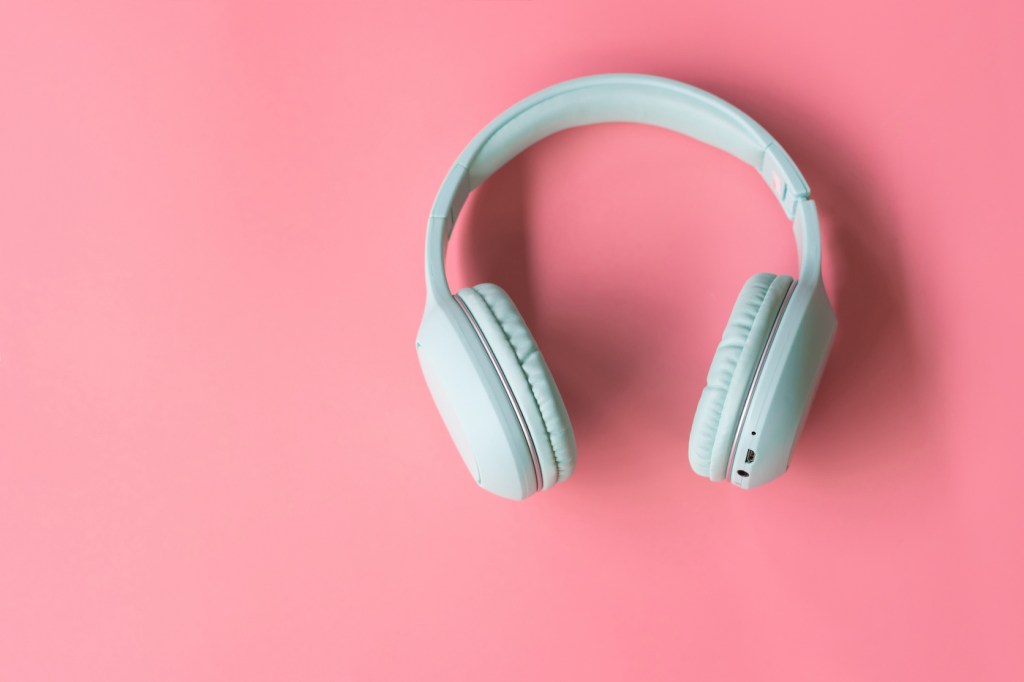 Wireless white headphones against a pink background