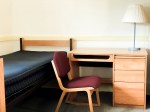 student dormitory room with bed, desk & chair