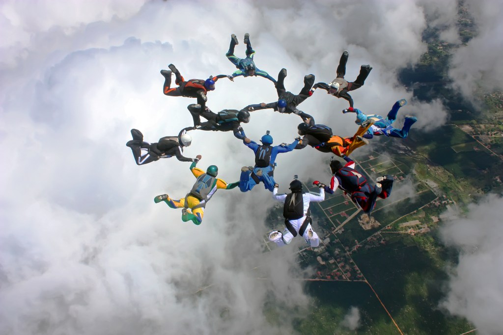 Skydivers make a formation above the clouds to symbolize network of partnerships