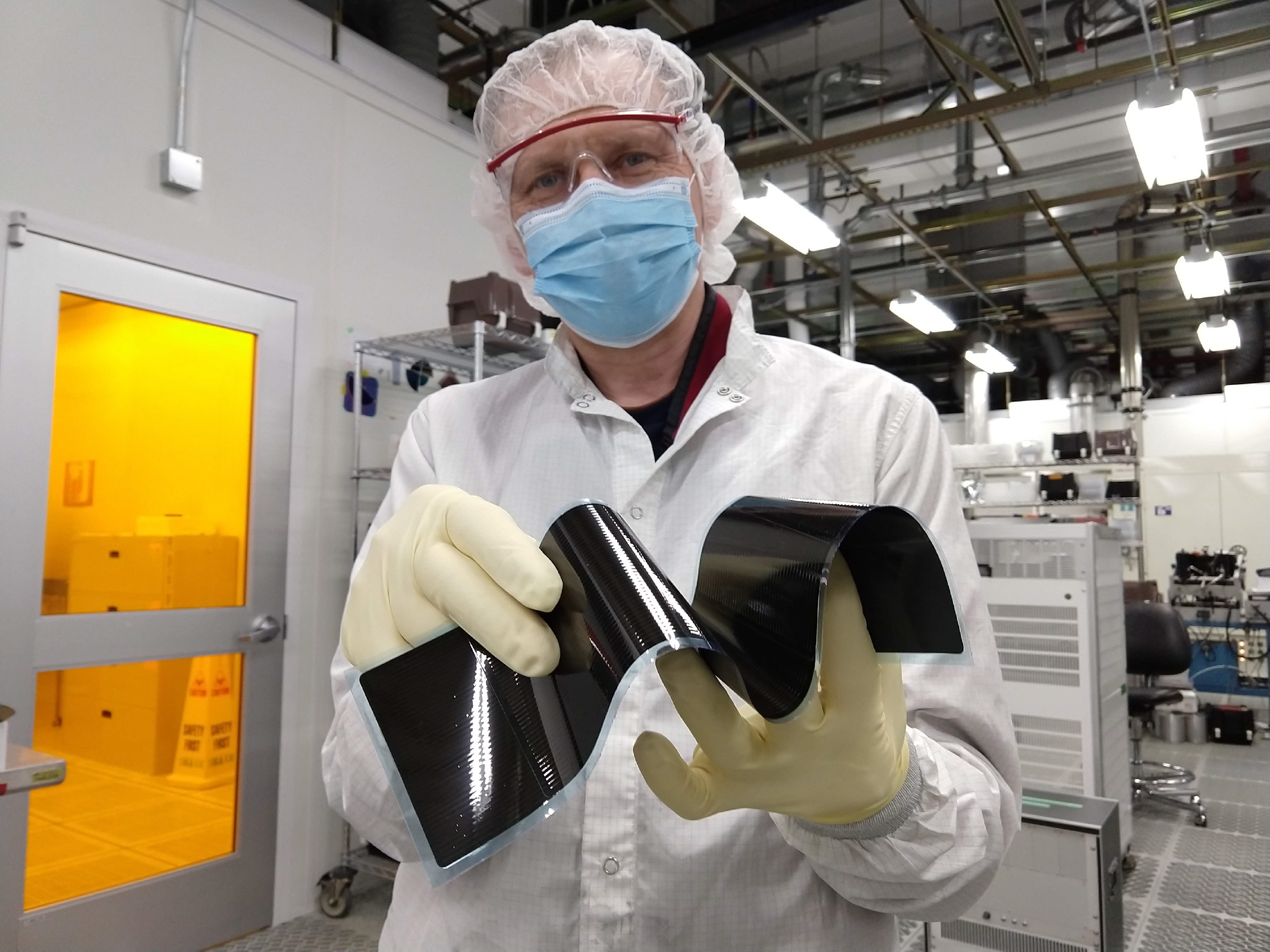 A lab technician shows the flexibility of a Regher "solar blanket."