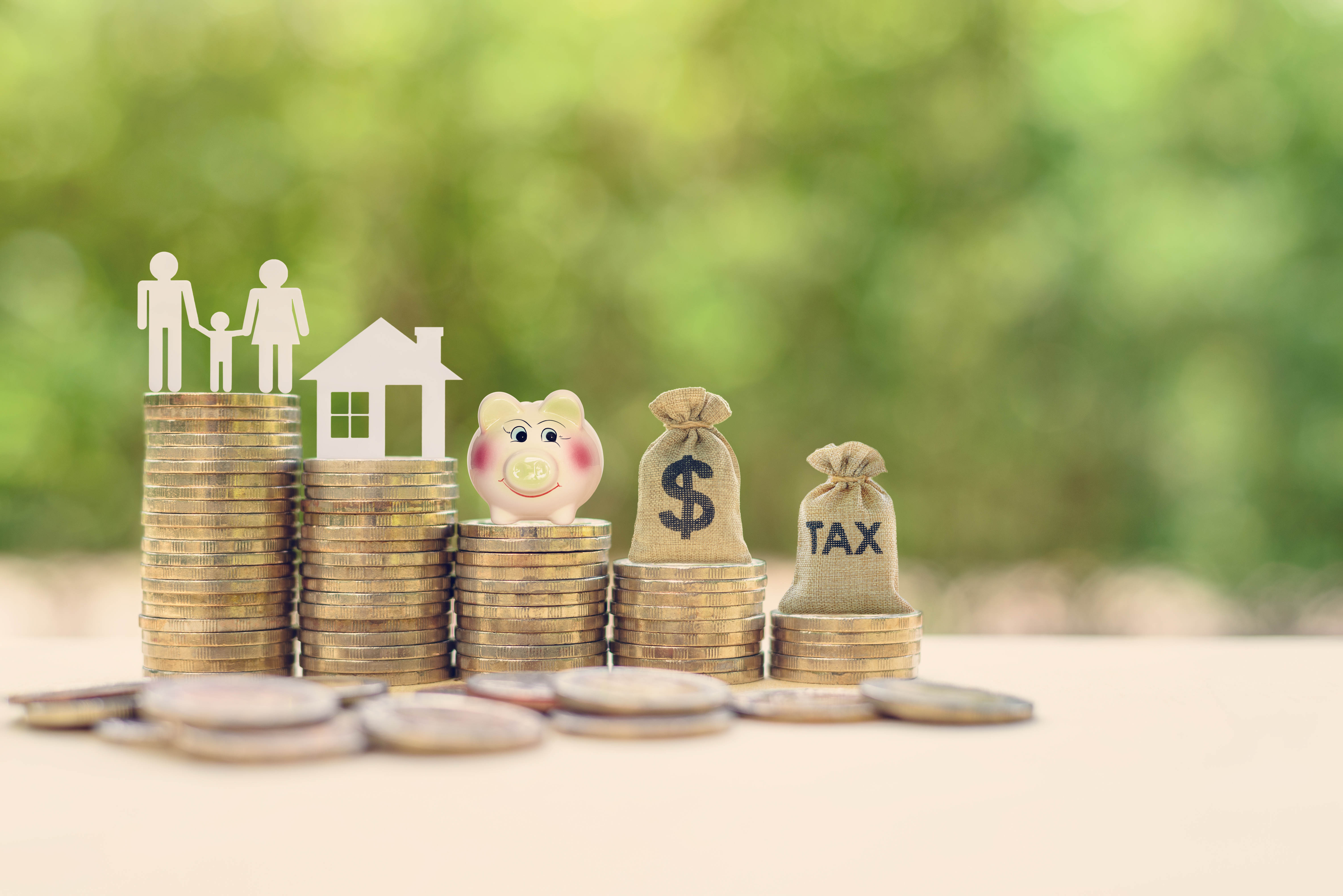 Image of a family, house, piggybank and bags of money stacked on top of coins to represent estate planning.