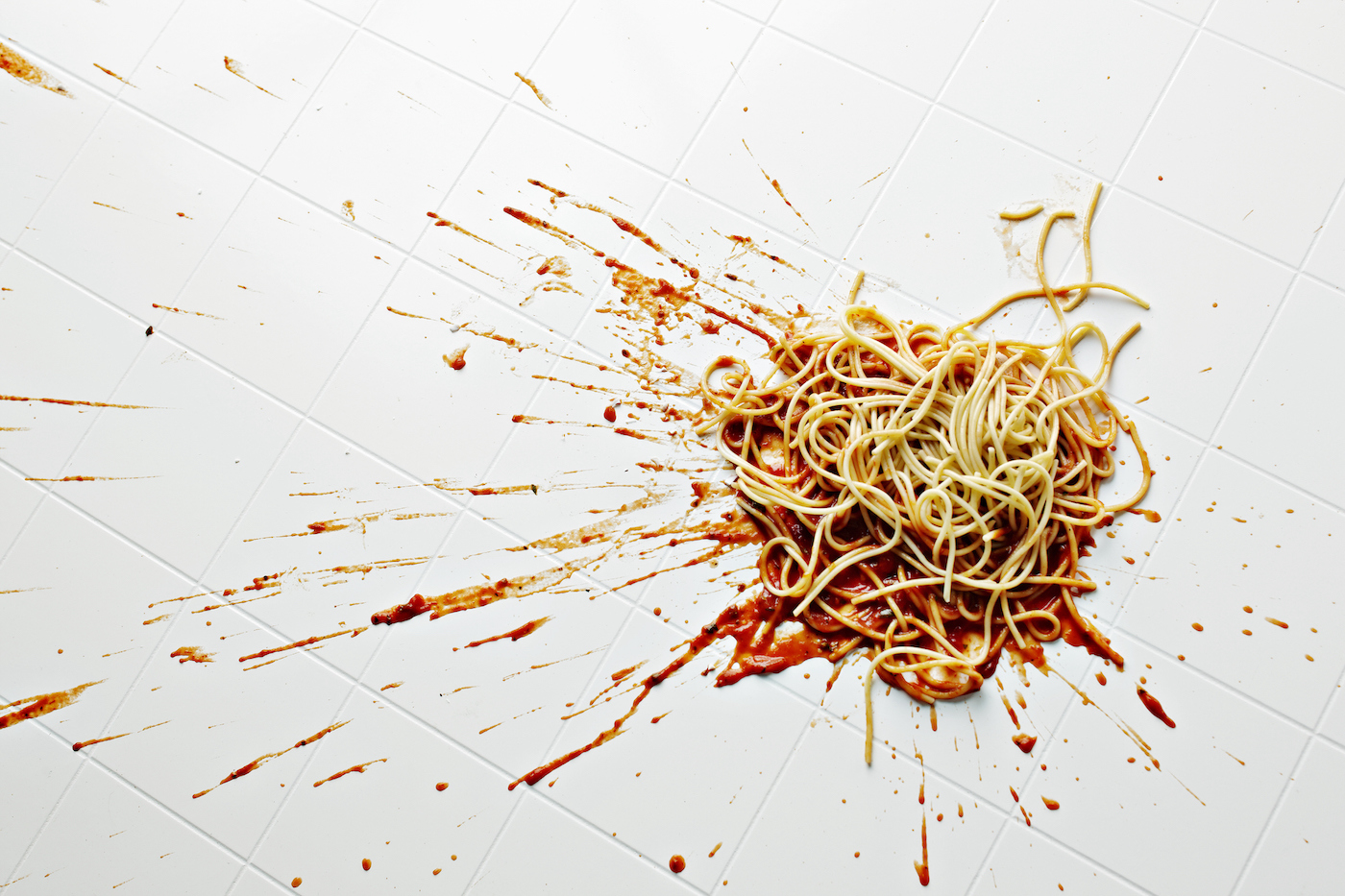 Spaghetti and sauce spilled on kitchen floor