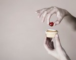 Hand placing cherry on top of cup cake