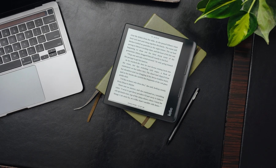 The Sage ereader on a table next to a laptop.