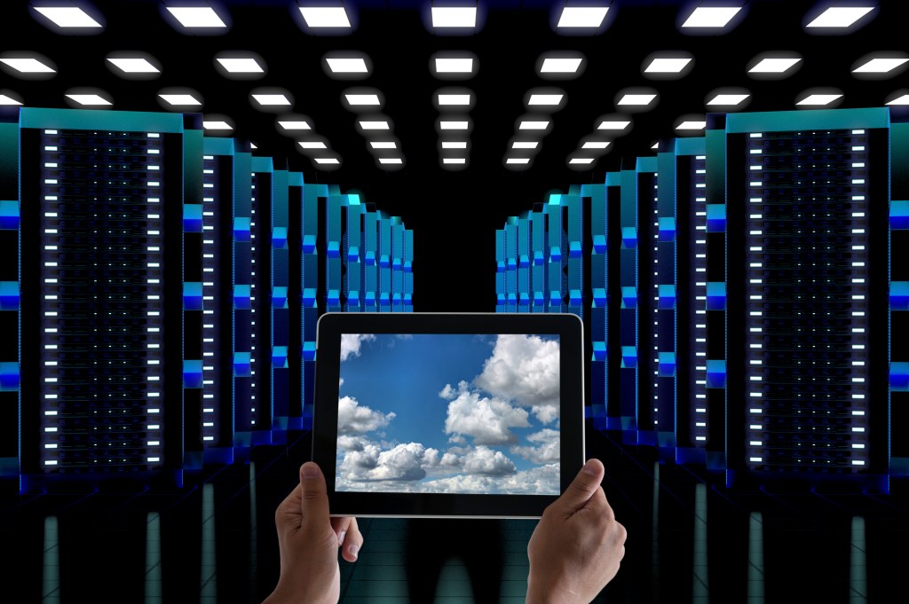 Tablet with picture of clouds inside data center with lots of servers.