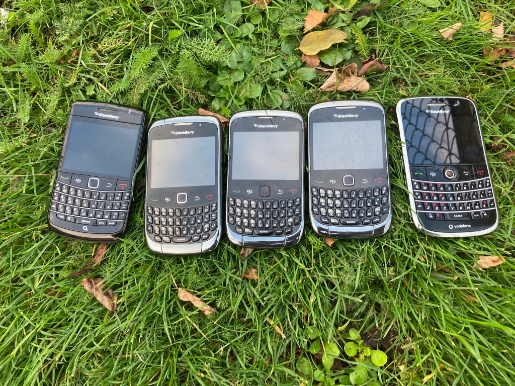 five blackberry phones sitting on the lawn