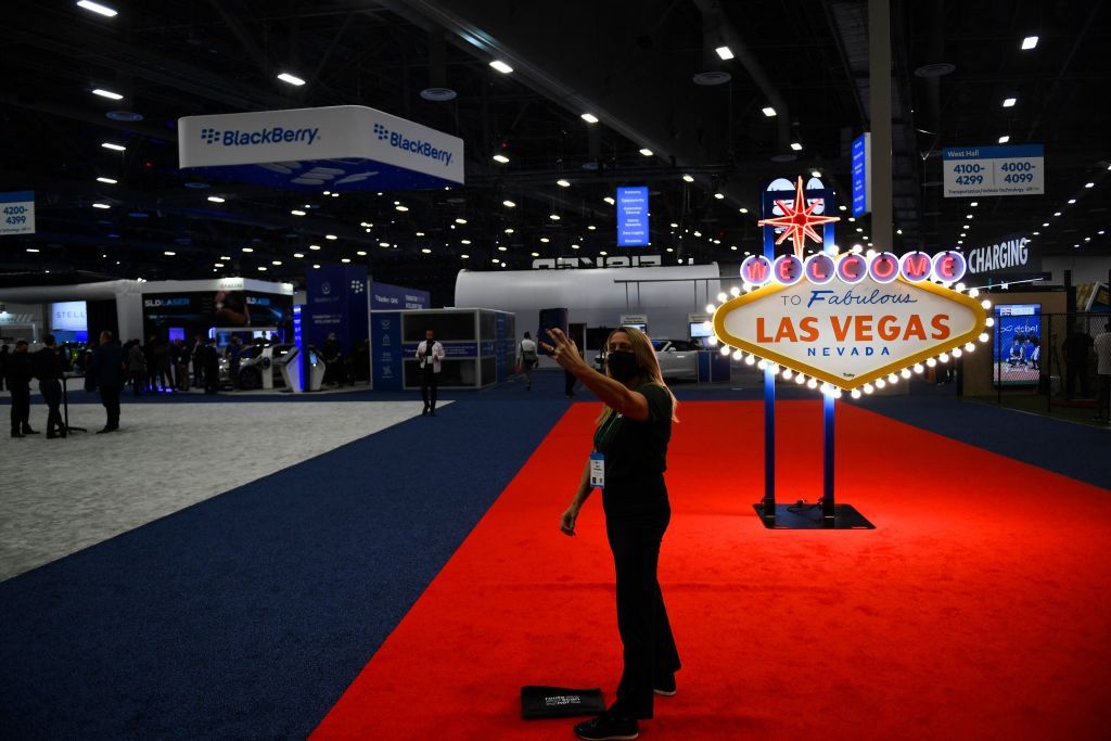 An attendee wears a face mask while taking a selfie in front of the Welcome To Fabulous Las Vegas sign on the show floor during the Consumer Electronics Show (CES) on January 6, 2022 in Las Vegas, Nevada. - The CES tech show threw open its doors Wednesday in Las Vegas despite surging Covid-19 cases in the United States, as one of the world's largest trade fairs tried to get back to business. Despite some obvious gaps on the showfloor -- after high-profile companies like Amazon and Google cancelled over climbing virus risk -- crowds of badge-wearing tech entrepreneurs, reporters and aficionados poured through venues. (Photo by Patrick T. FALLON / AFP) (Photo by PATRICK T. FALLON/AFP via Getty Images)