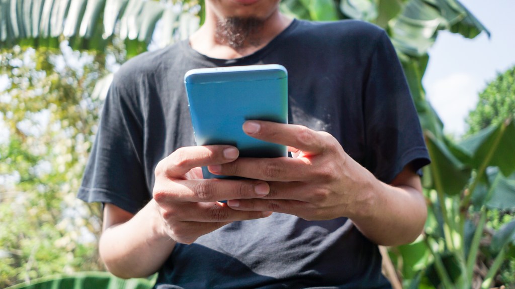 Photo of man in Indonesia holding smartphone, used in post about investment app Pluang
