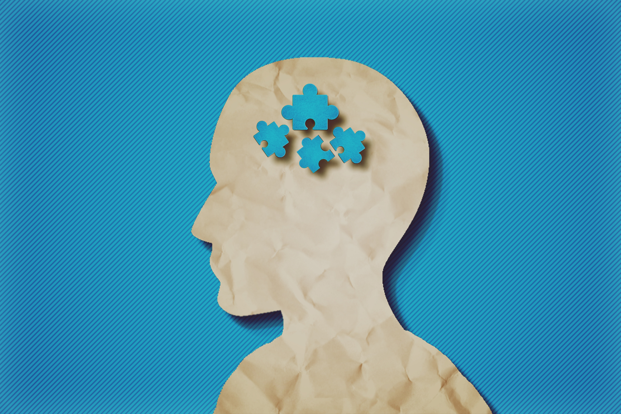 paper head with puzzle pieces-Autism concept.Blue background