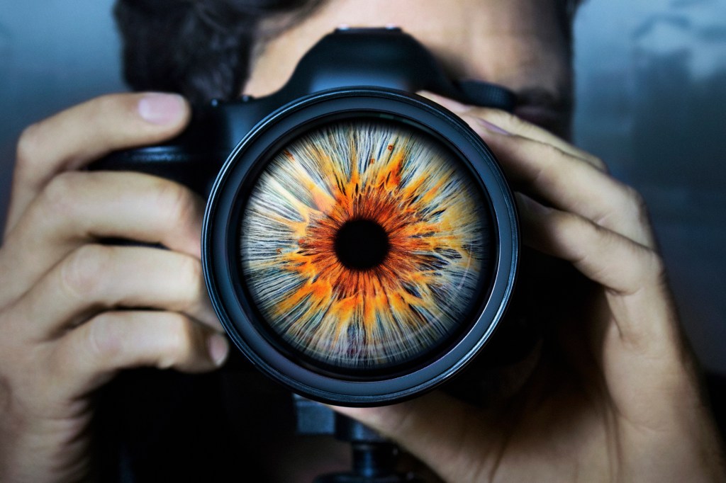 Man holding camera with iris as lens