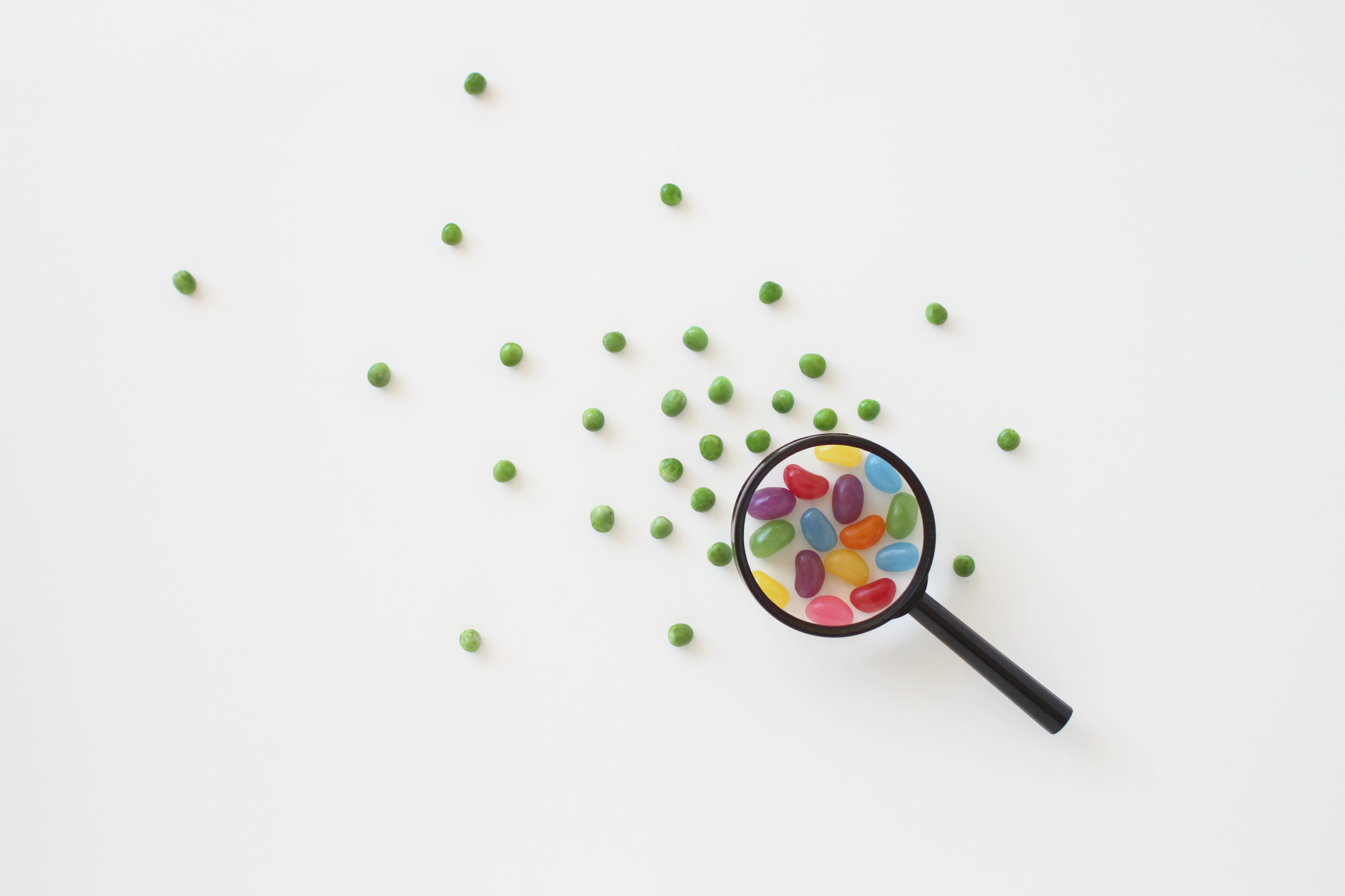 Image of jellybeans under a magnifying glass surrounded by peas to represent regulatory oversight.