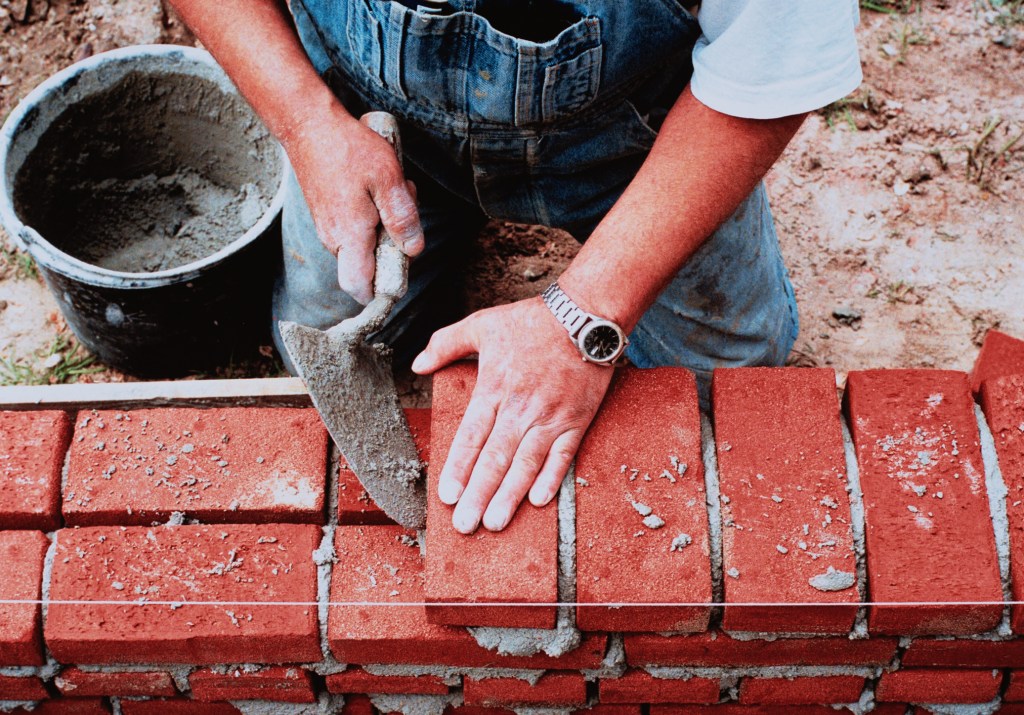Close-up of hands laying bricks, used in an article about Southeast Asian open finance API startup Brick