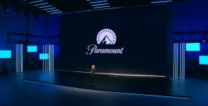 Woman speaking onstage in front of screen with large Paramount logo