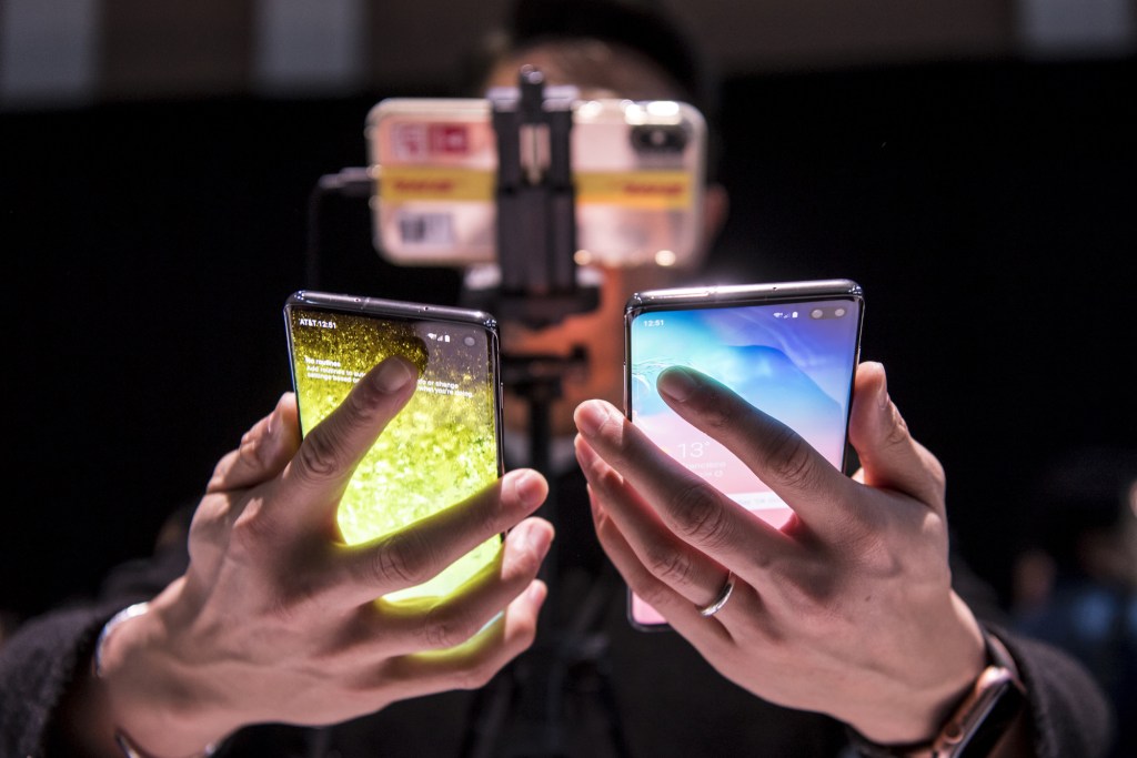 Mężczyzna trzyma dwa telefony Samsung, po jednym w każdej ręce, na imprezie Samsung 2019.