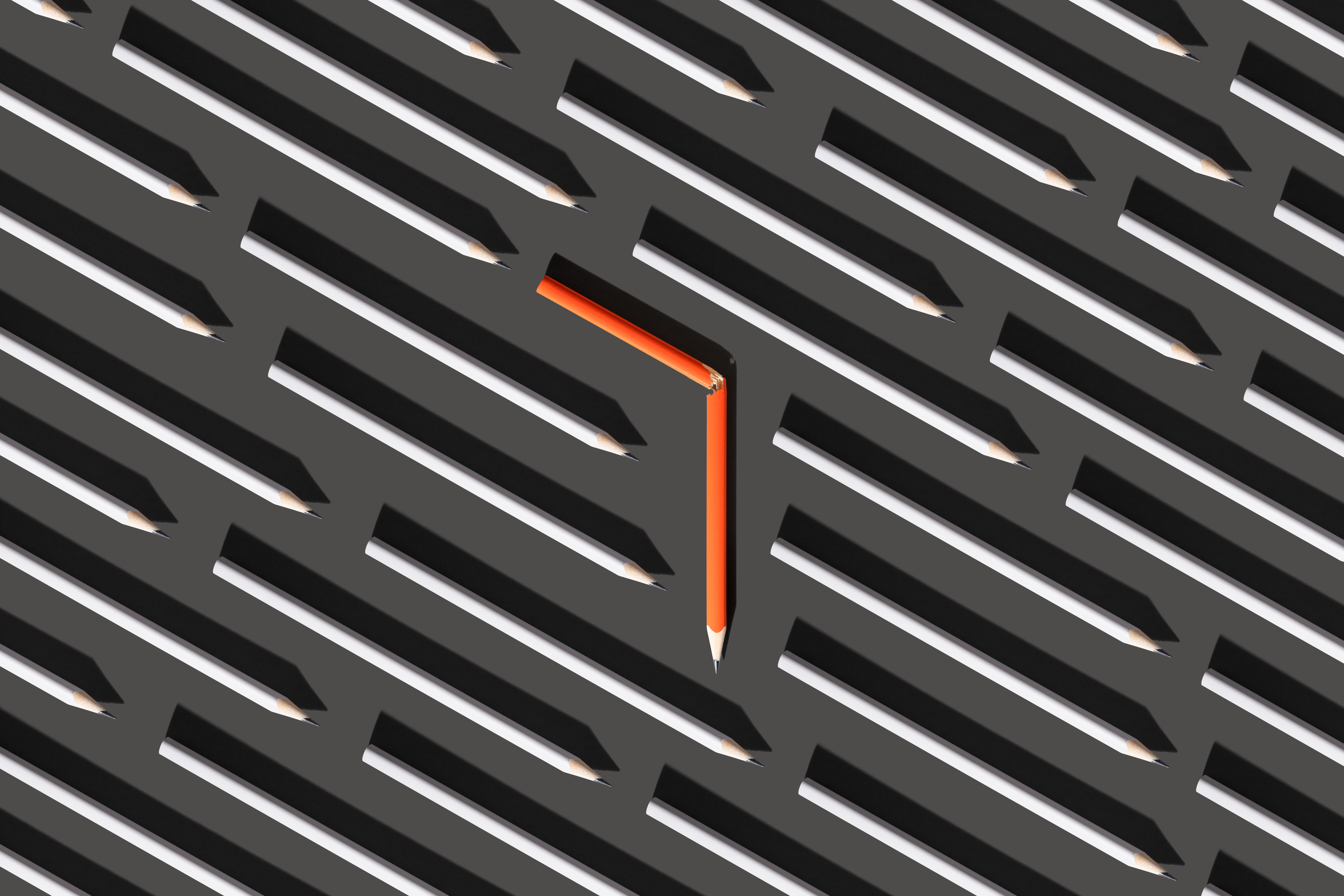 Image of an orange broken pencil amid straight gray pencils to represent pivoting.