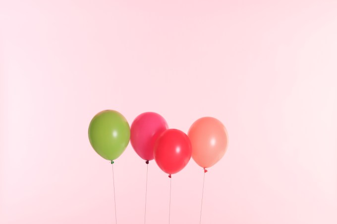 Image of four balloons against a pale pink background.
