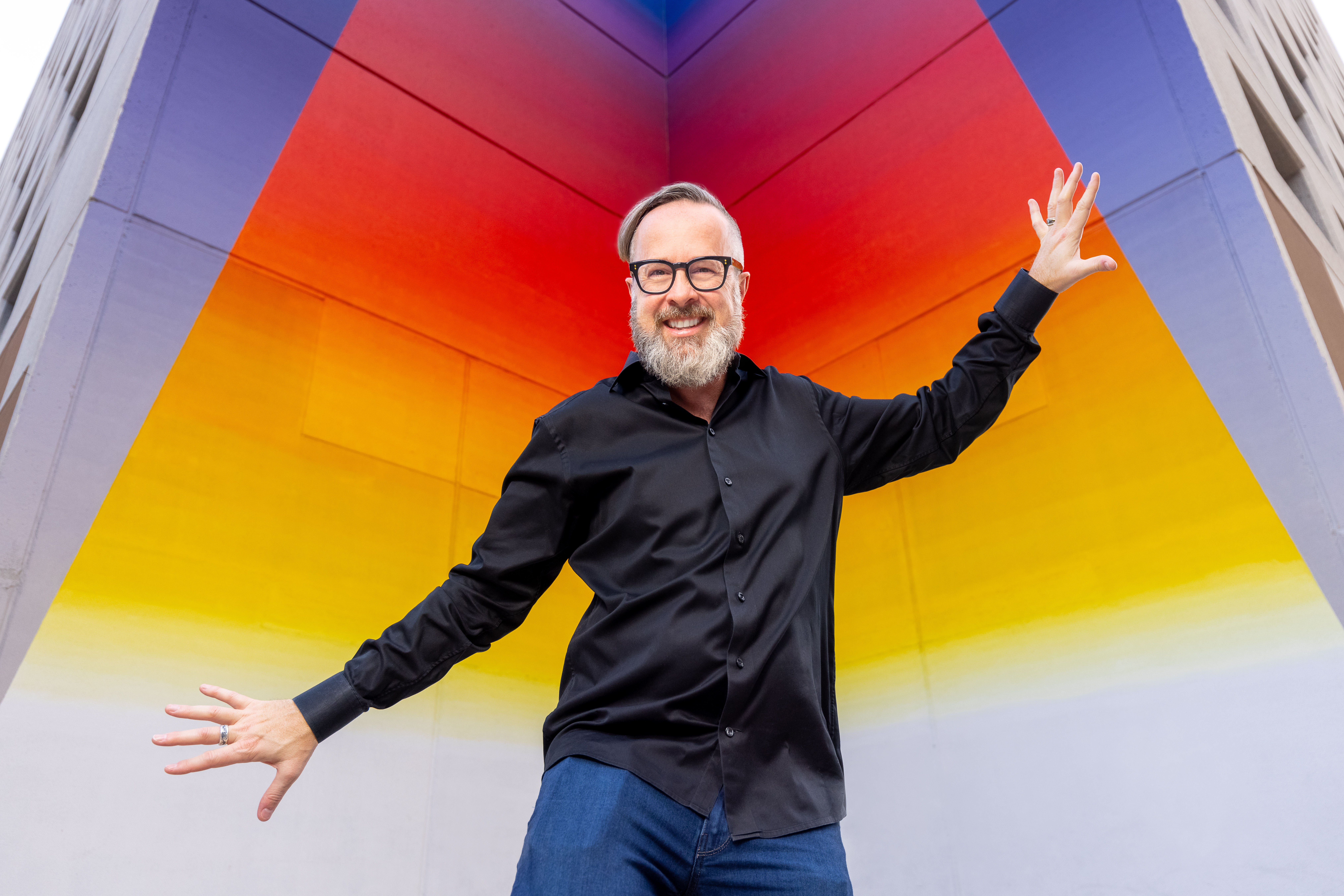 Austin-based serial entrepreneur Will Hurley posing with arms outstretched in front of a wall