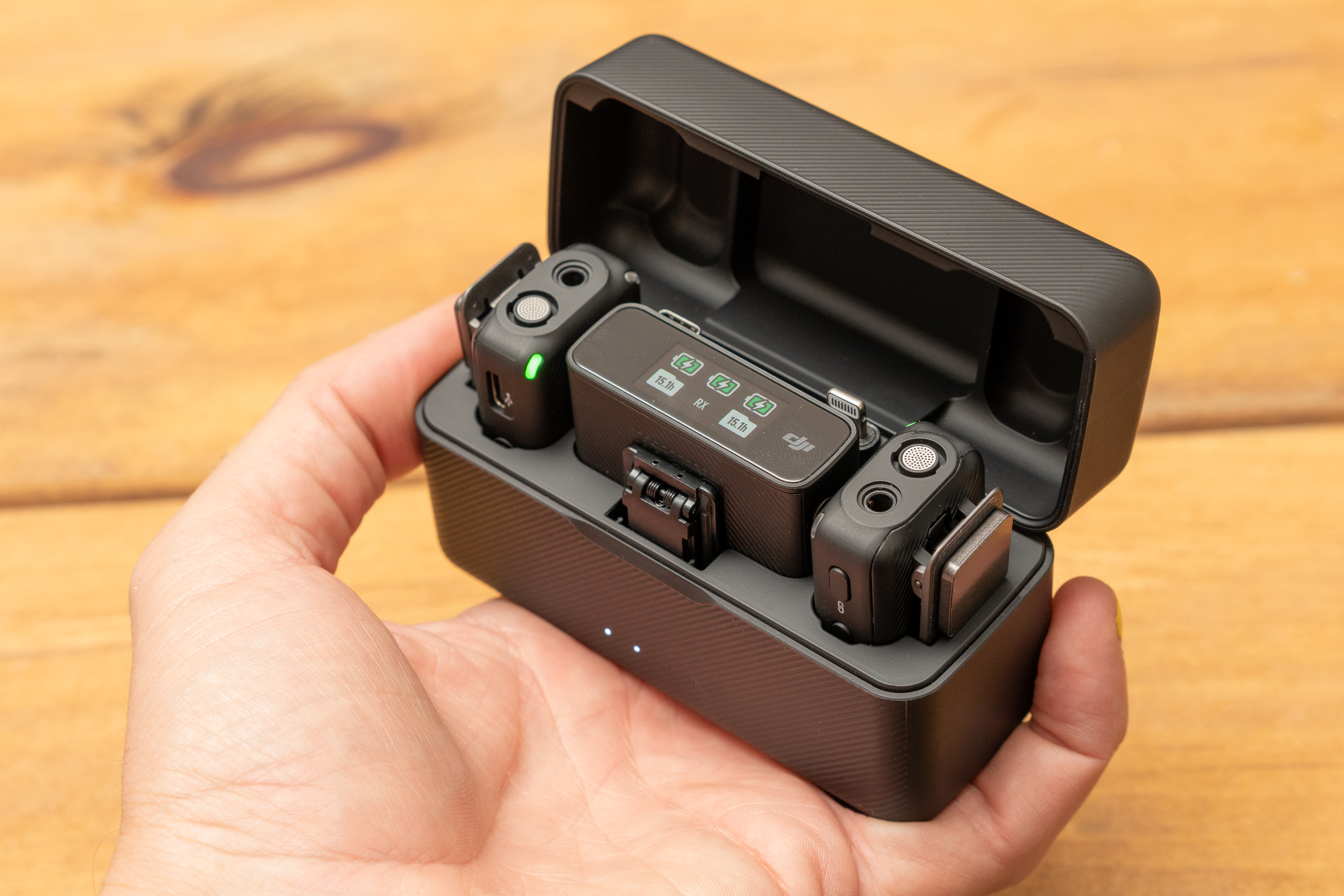 DJI MIc box, open with microphones and receivers showing, held in a hand for size