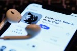 earbuds laid over smartphone showing Clubhouse app