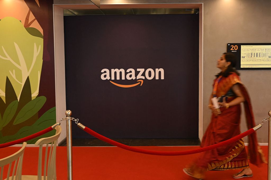 A worker walks past a logo of Amazon during the inaugural of Amazons second largest office space in Chennai.