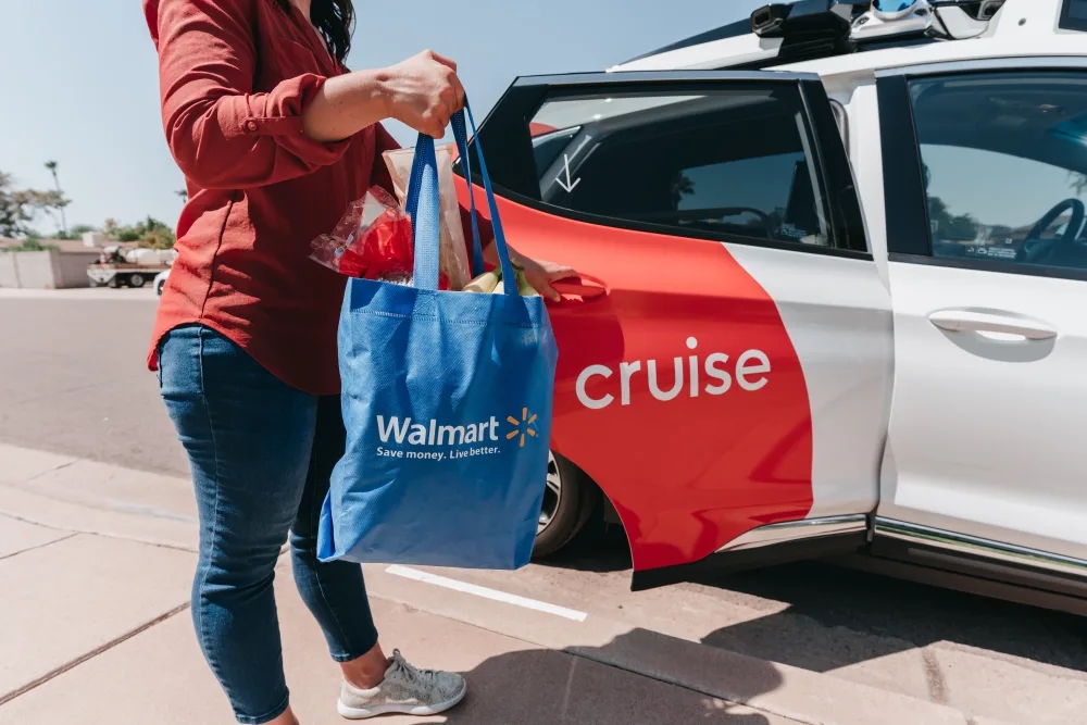 Walmart customer grabbing order from Cruise Chevy Bolt EV self-driving delivery