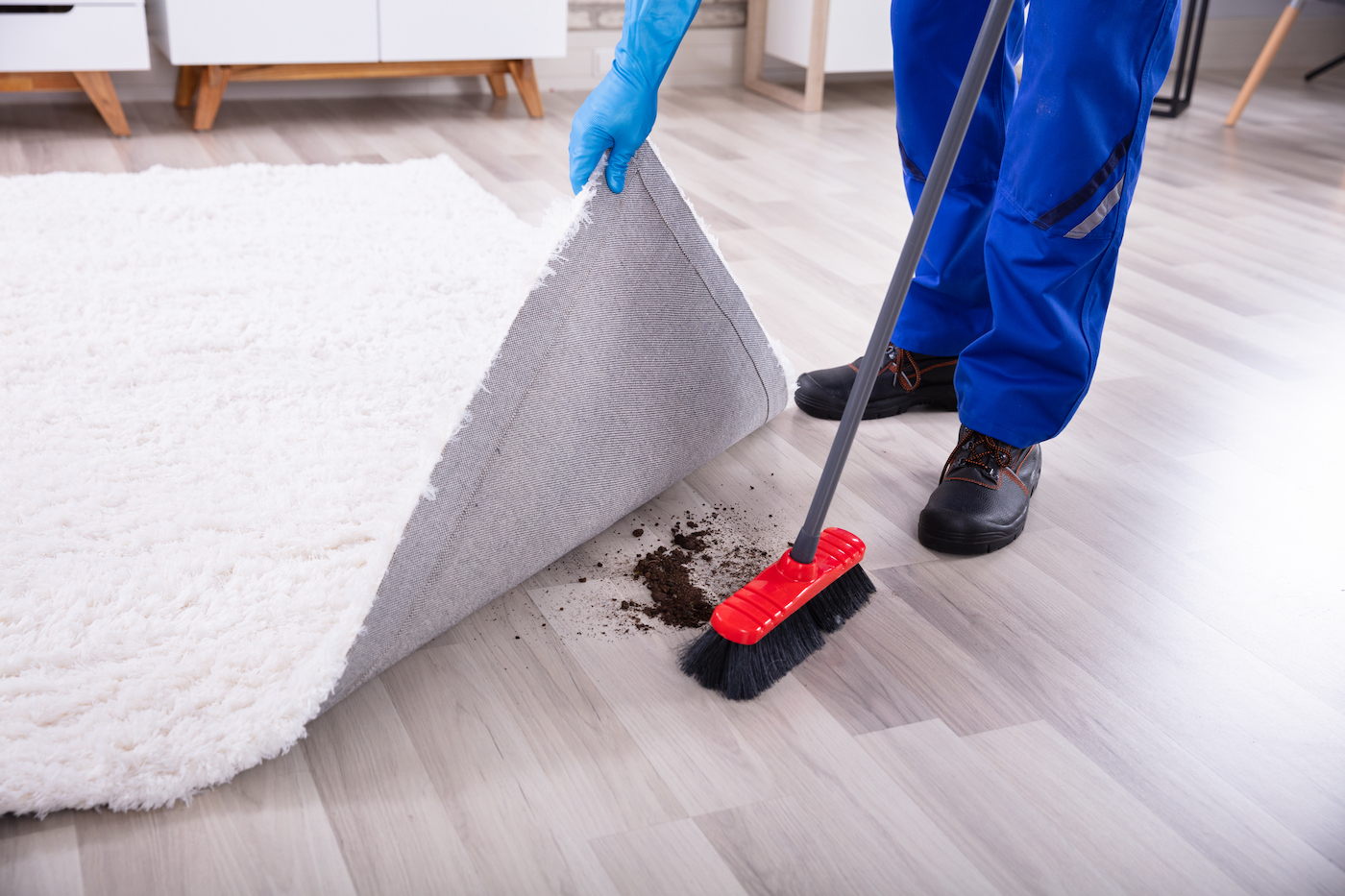 Low section view of janitor cleaning dirt under carpet with mop