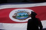 Silhouette of an honor guard in front of a flag of Costa Rica