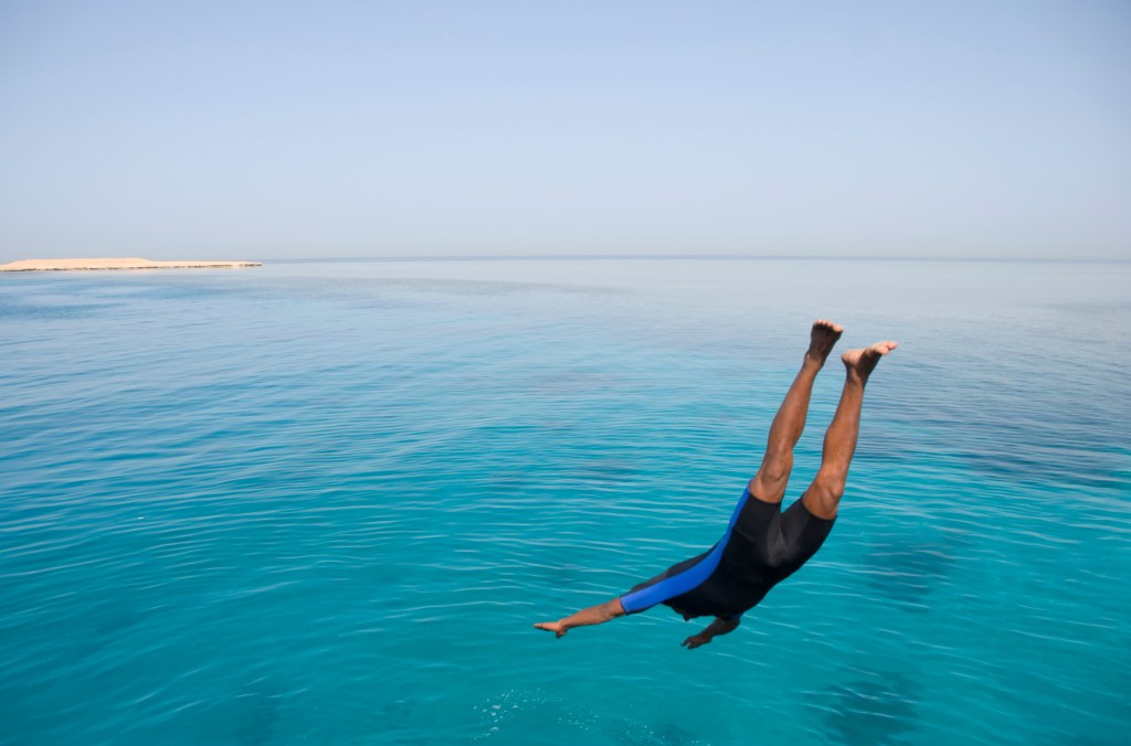 Man diving into the ocean caught in mid dive.