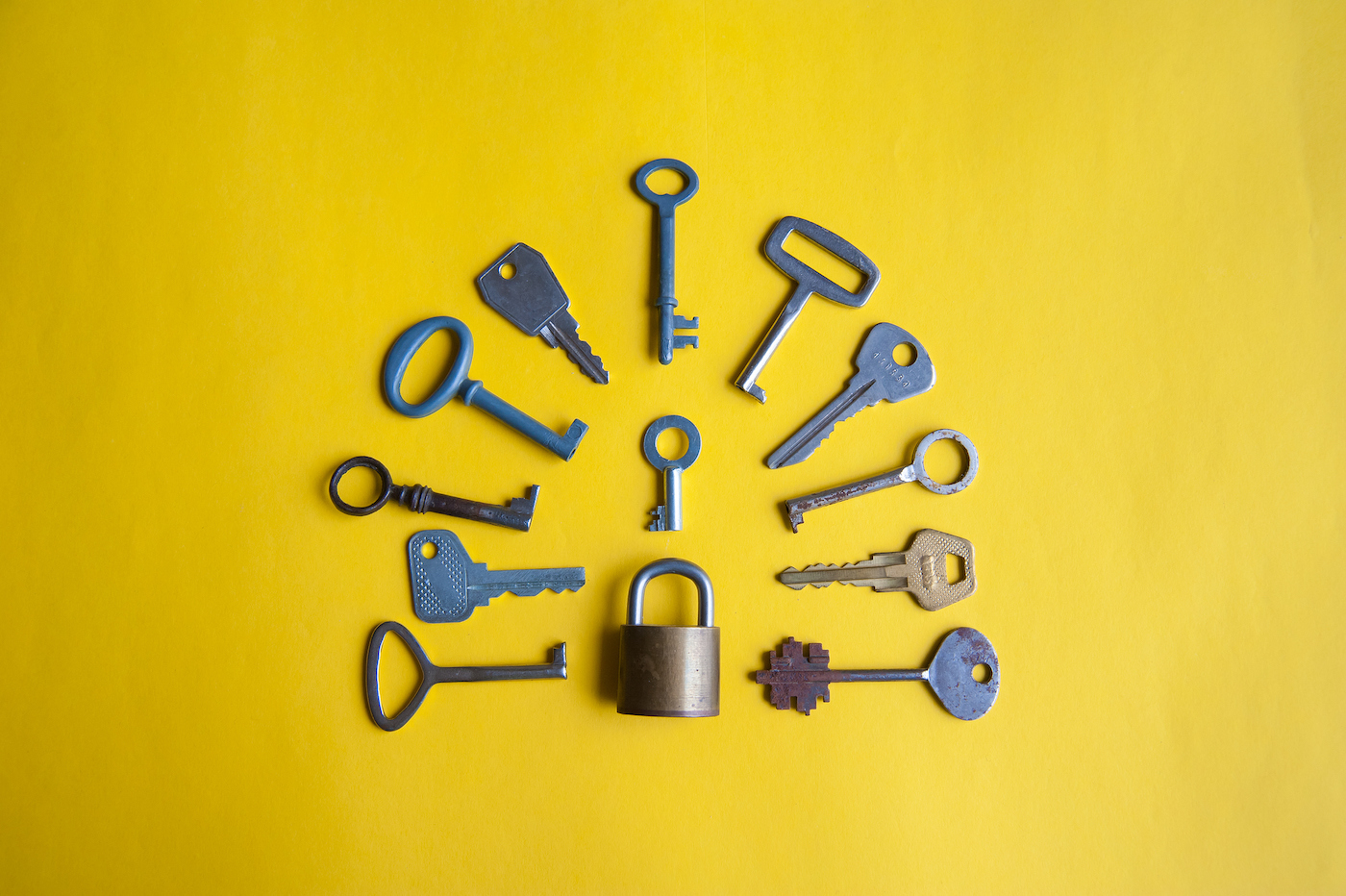 One lock and many different keys lie on a yellow background