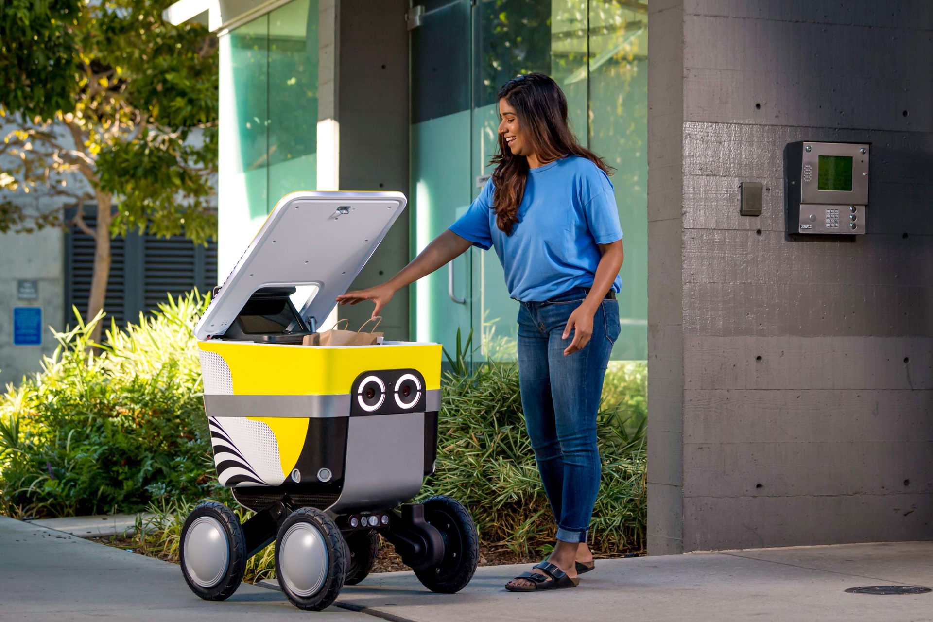 Woman accessing an Uber Eats autonomous sidewalk delivery with Serve Robotics