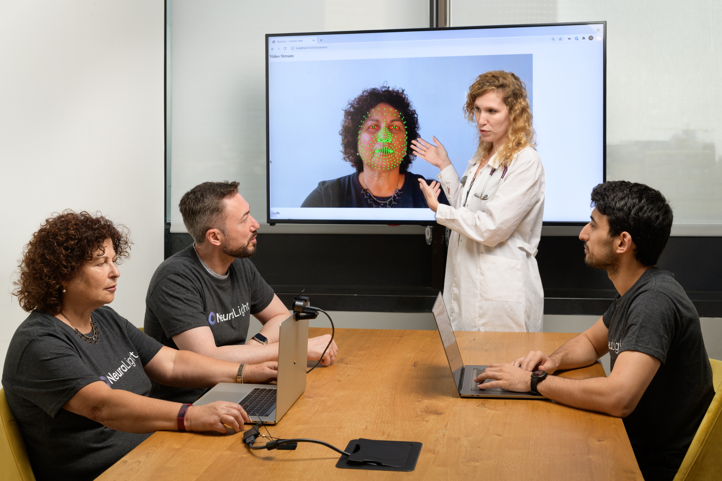 A meeting in an office showing digital readings of a preson's face.