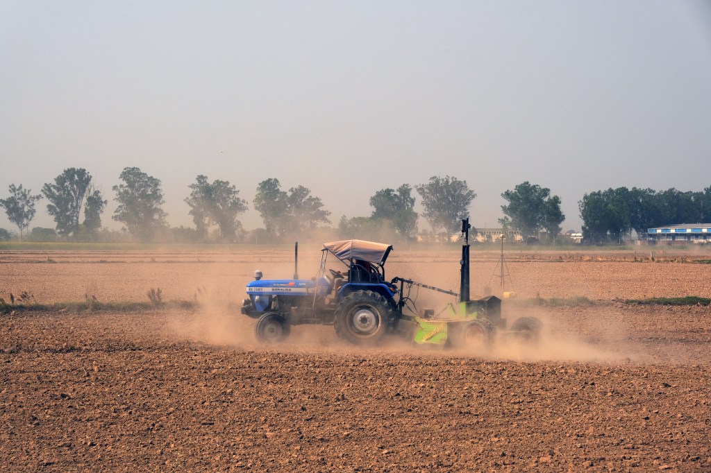 A farmer on tractor prepares his wheat fields for the next crop in the Ludhiana district of Punjab, India.