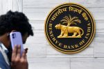 man on mobile phone walking past Reserve Bank of India sign