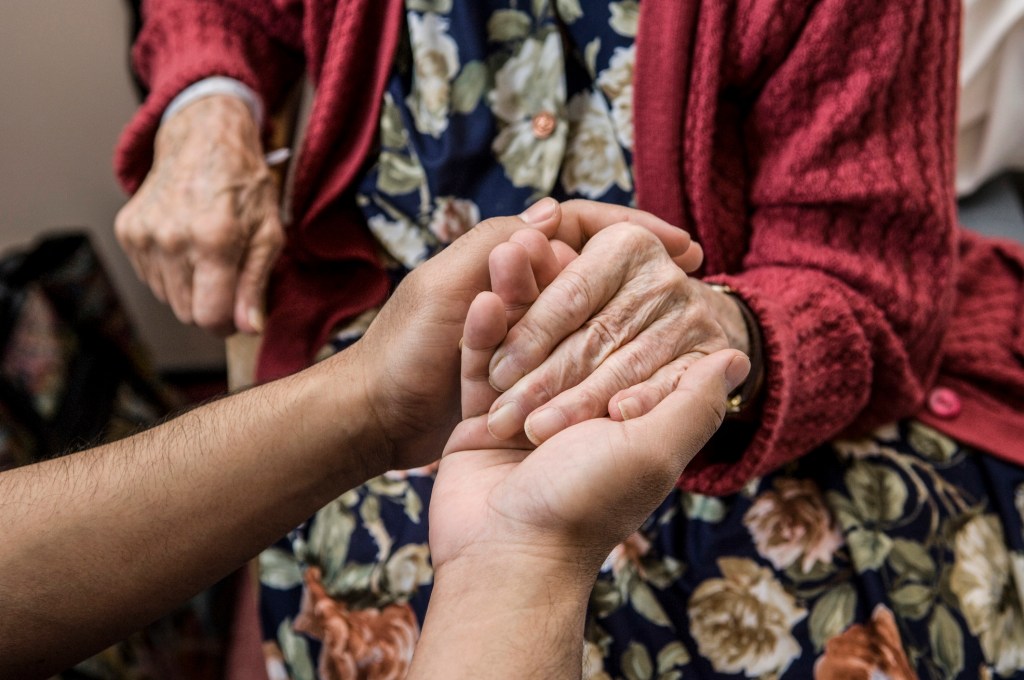 Nurse holding hands with elderly patient.Nurse holding hands with elderly patient, used in a post about August Health