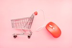 Still life of a small shopping cart and red computer mouse; e-commerce market 2022