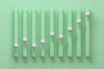 Digital generated image of abstract vertical bar chart made out of smooth round green vertical bars with white spheres on each bar on green background.