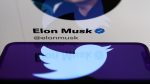 Twitter logo displayed on a phone screen and Elon Musk's Twitter account displayed on a laptop screen