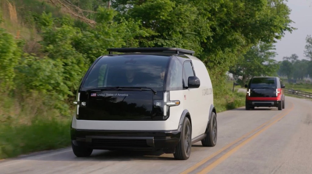 Two Canoo EVs drive on a road in Bentonville, Arkansas.