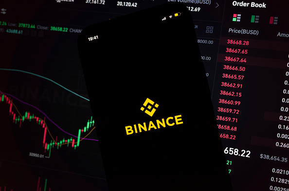 In this photo illustration, an iPhone displays the app and logo of popular cryptocurrency exchange platform Binance, with the desktop version in the background displaying market trends and exchange rates for cryptocurrency Bitcoin on 8th March, 2022 in Leeds, United Kingdom. (photo by Daniel Harvey Gonzalez/In Pictures via Getty Images)