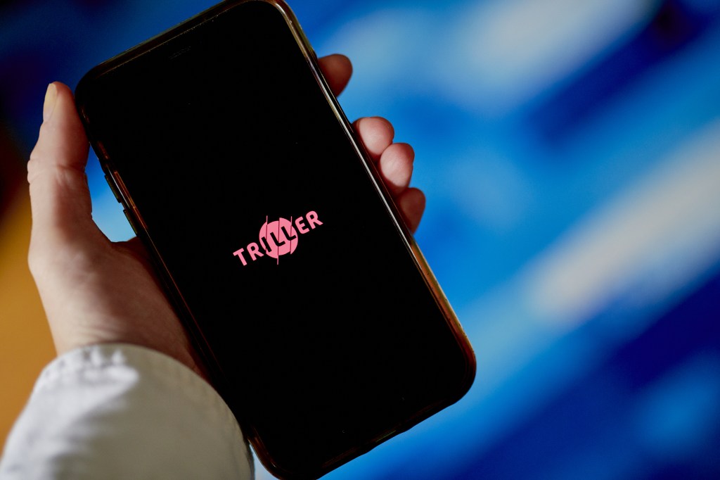 The logo for Triller is displayed on a smartphone in an arranged photograph