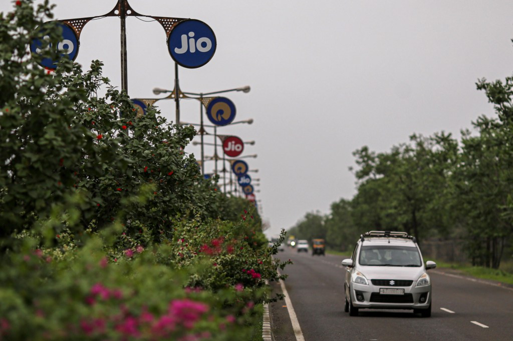 car on road driving past Jio signs