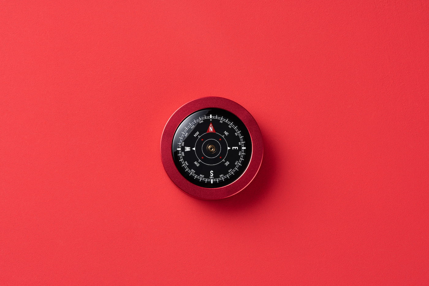 Red color navigation compass on red background directly above view.