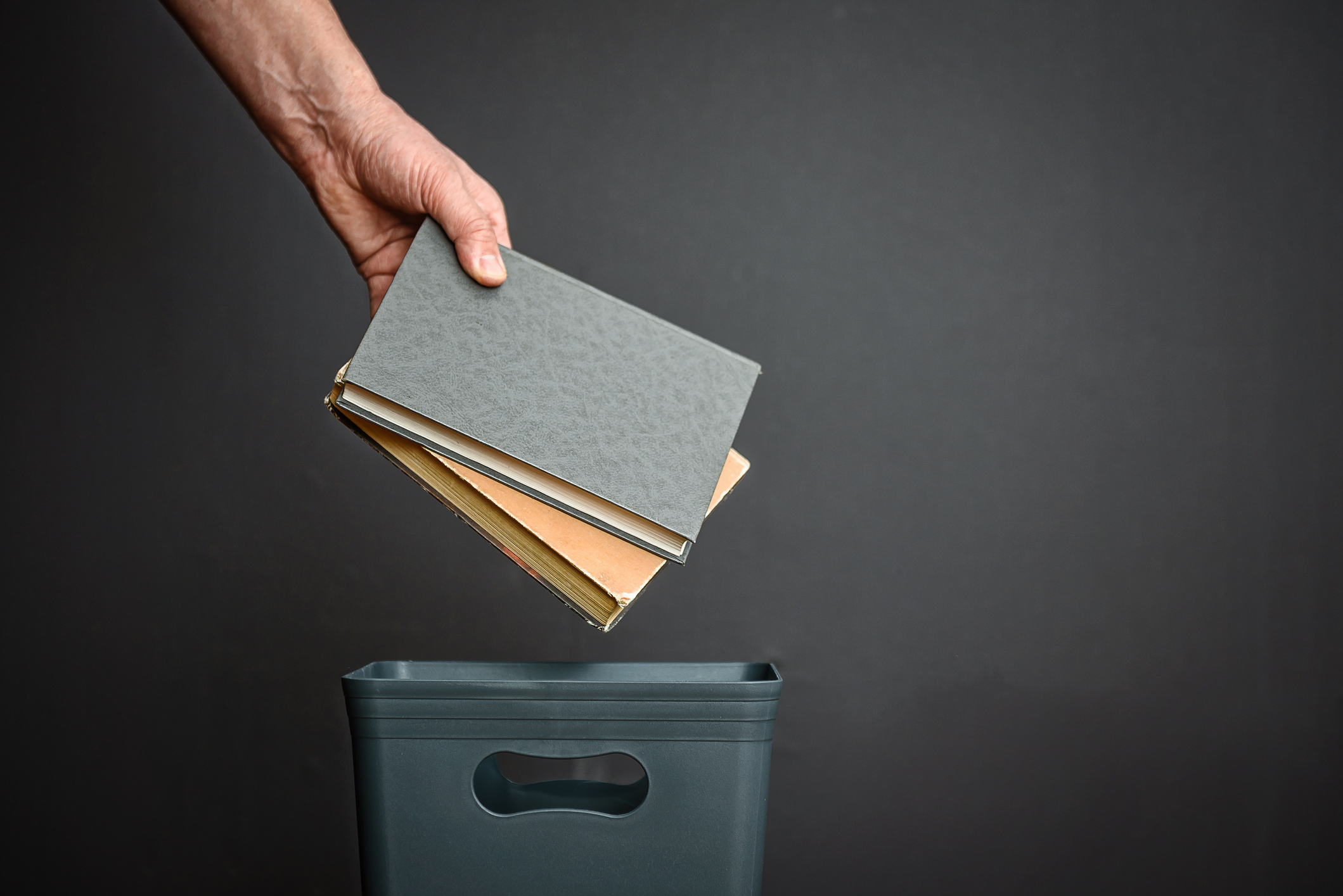 hand throwing old books into the trash; unlearn the lessons of the 2021 fundraising boom