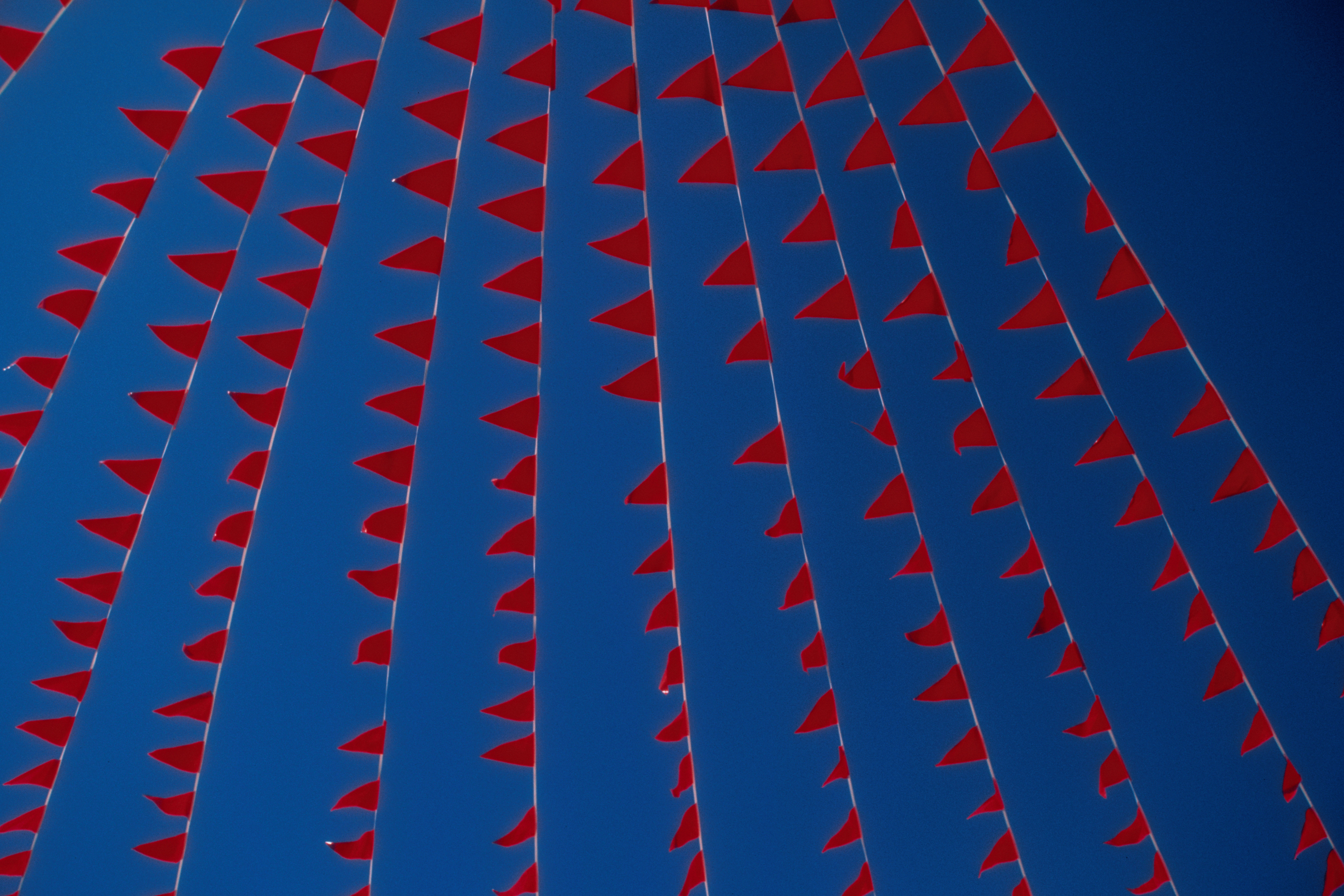 Image of red flags against a blue sky.