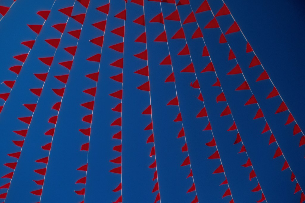 Image of red flags against a blue sky.
