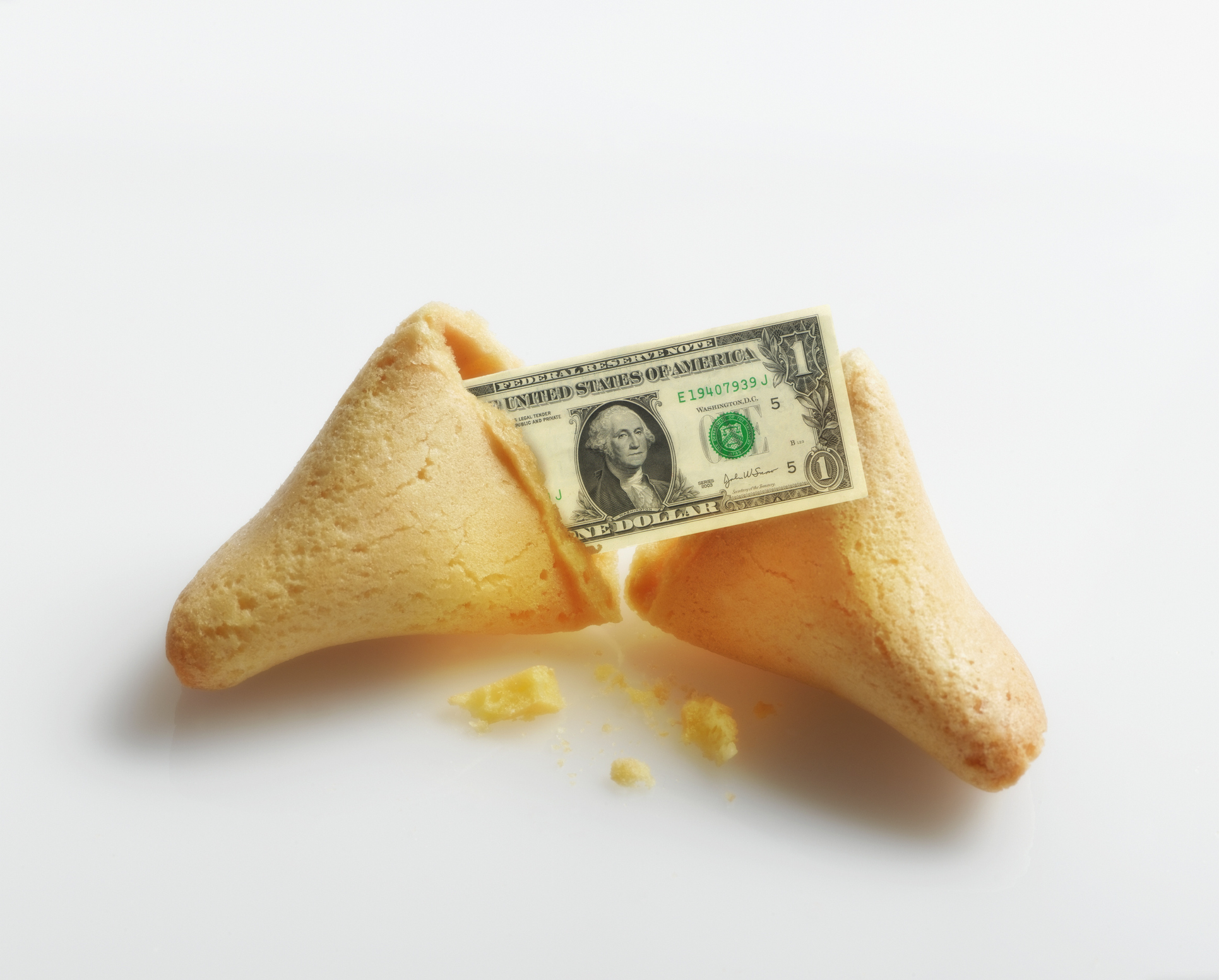 A broken fortune cookie with a US dollar inside