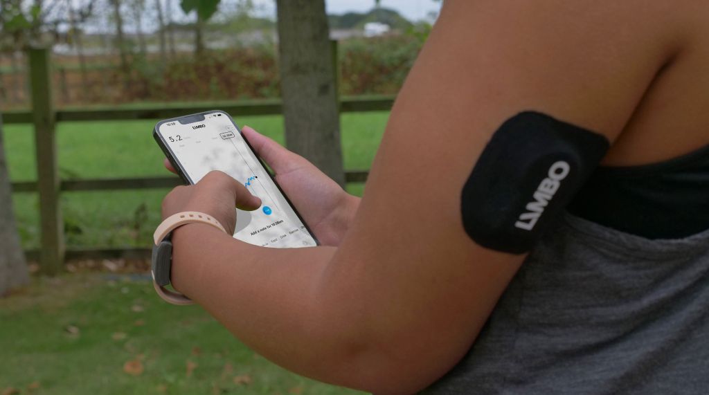 Limbo biosensor shown worn on the arm with the person holding the companion app
