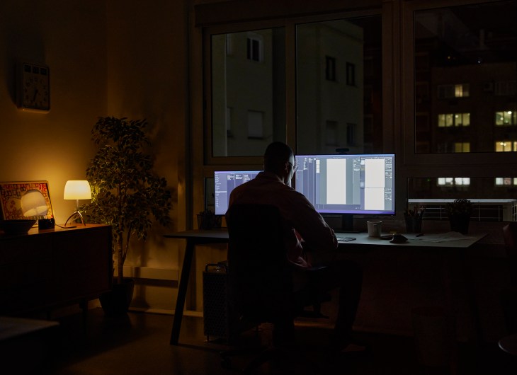 A home office in the dark with a person working at a computer.
